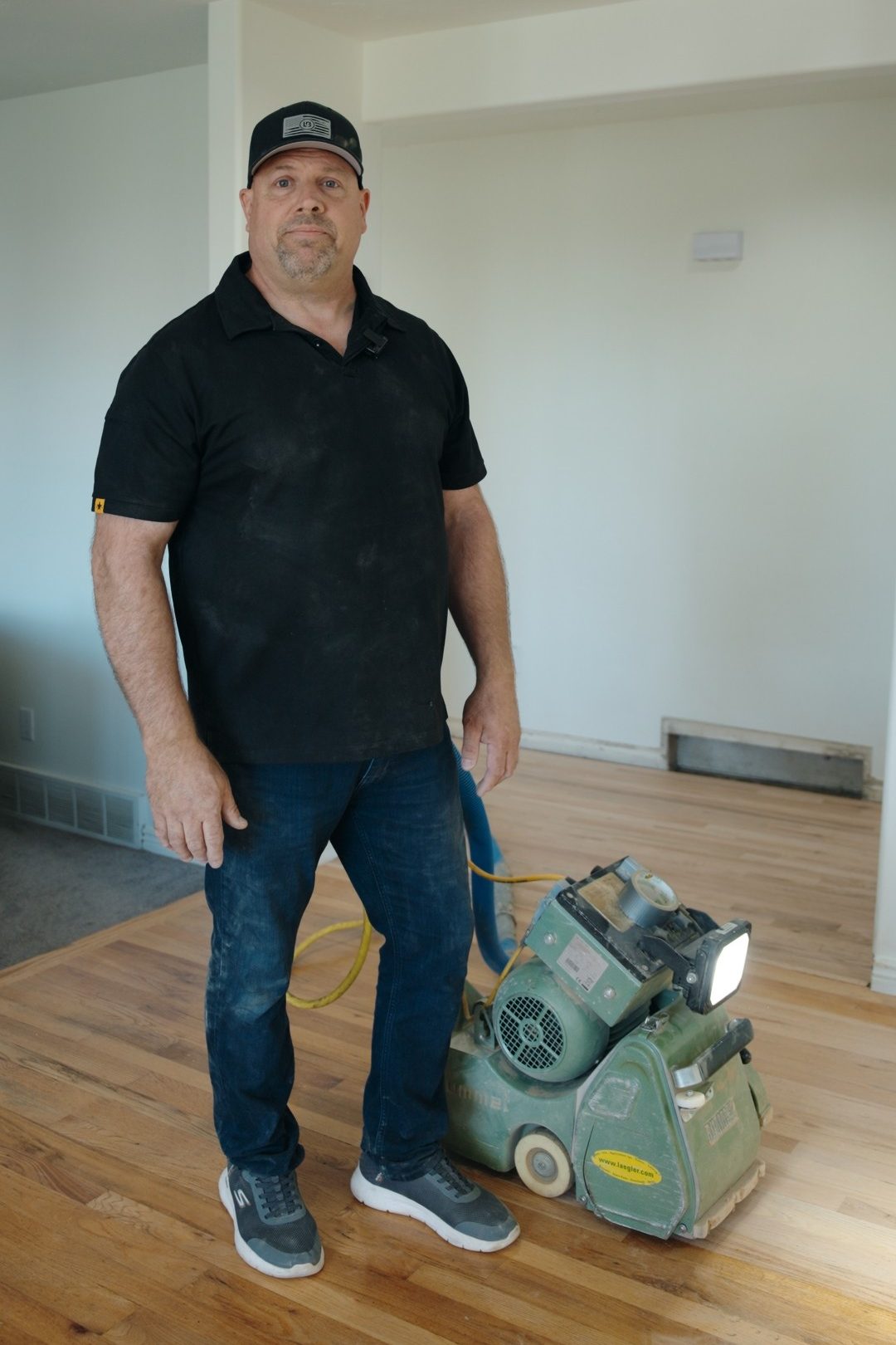 Shaun Humphreys, owner of ADF Flooring, standing on a freshly sanded oak floor beside his dust-containment floor sander